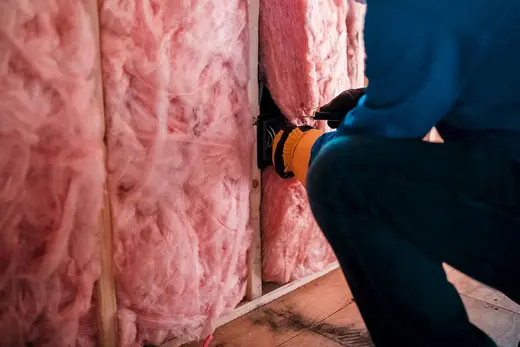 Profissional colocando lã mineral na parede (imagem ilustrativa)